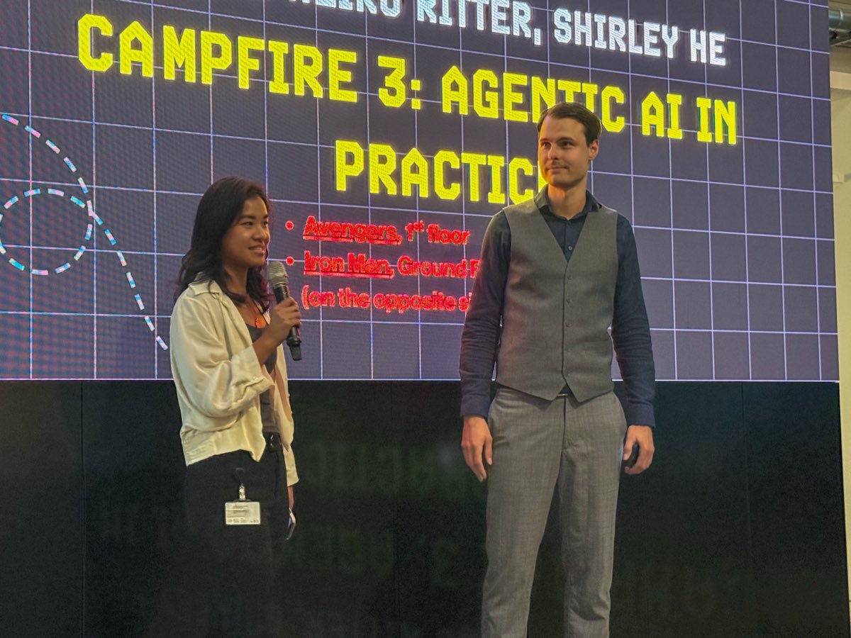 Shirley He on stage with a microphone, opening Campfire 3: Agentic AI in Practice