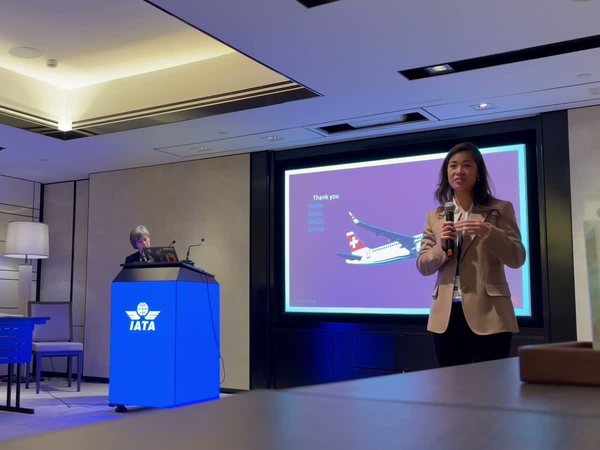 Shirley He speaking at the IATA World Data Symposium, an IATA lectern beside her